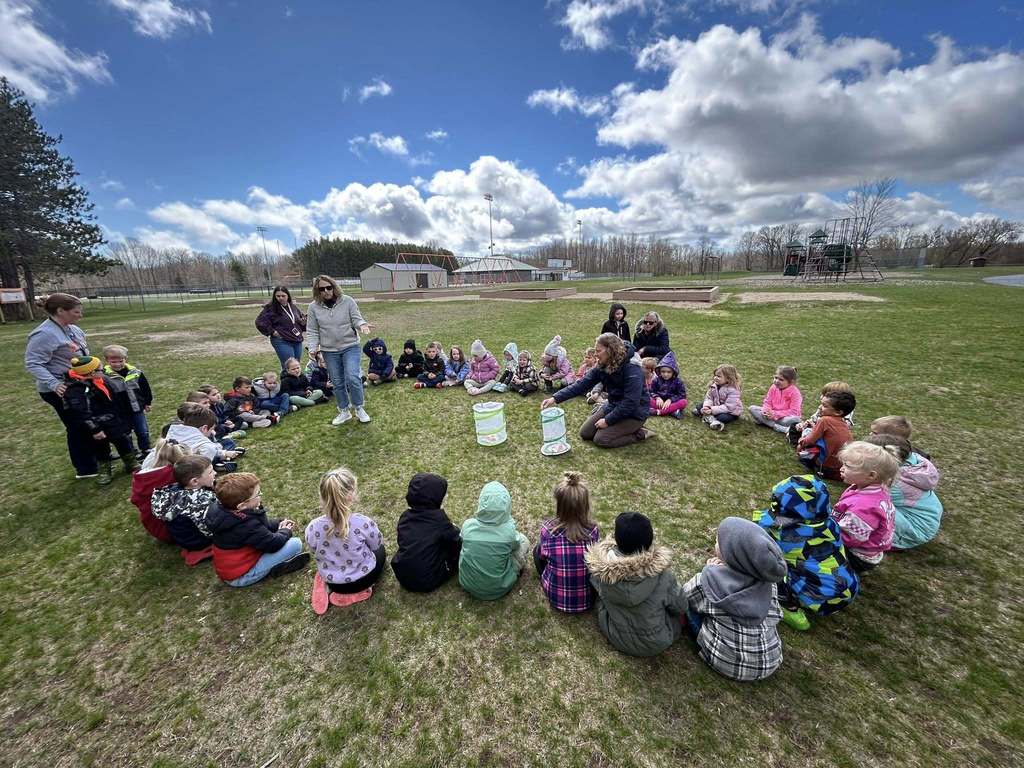 Students sit in circle outdoors while learning about butterflies