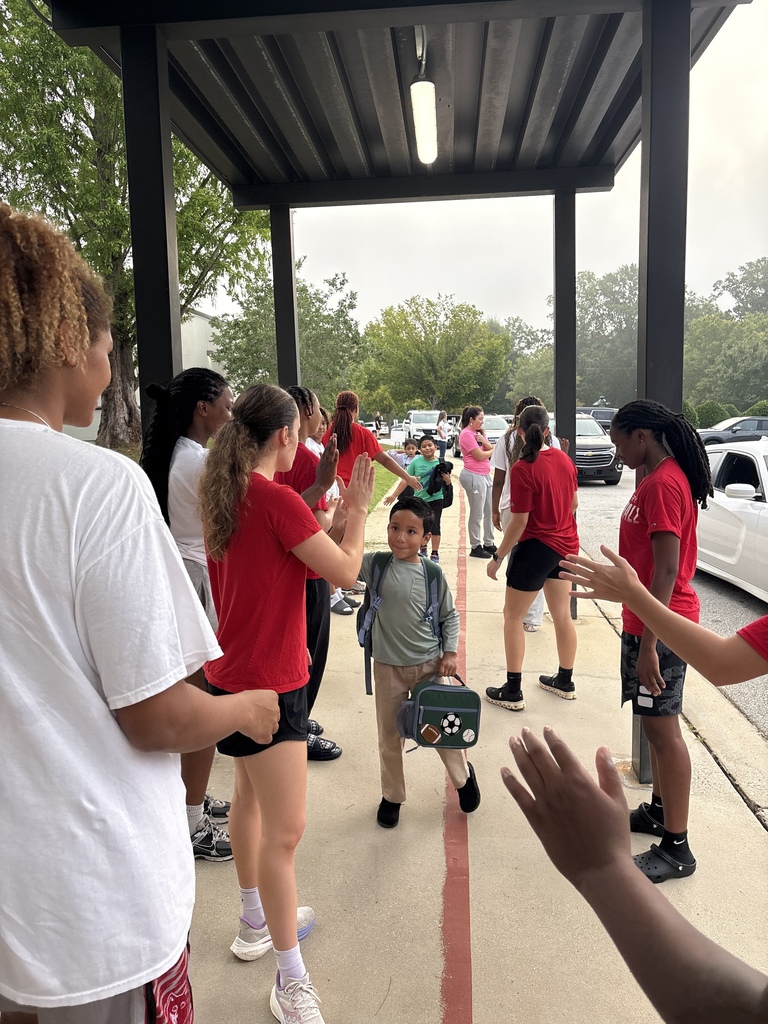 Wide shot of Newberry College basketball women players greeting a student.