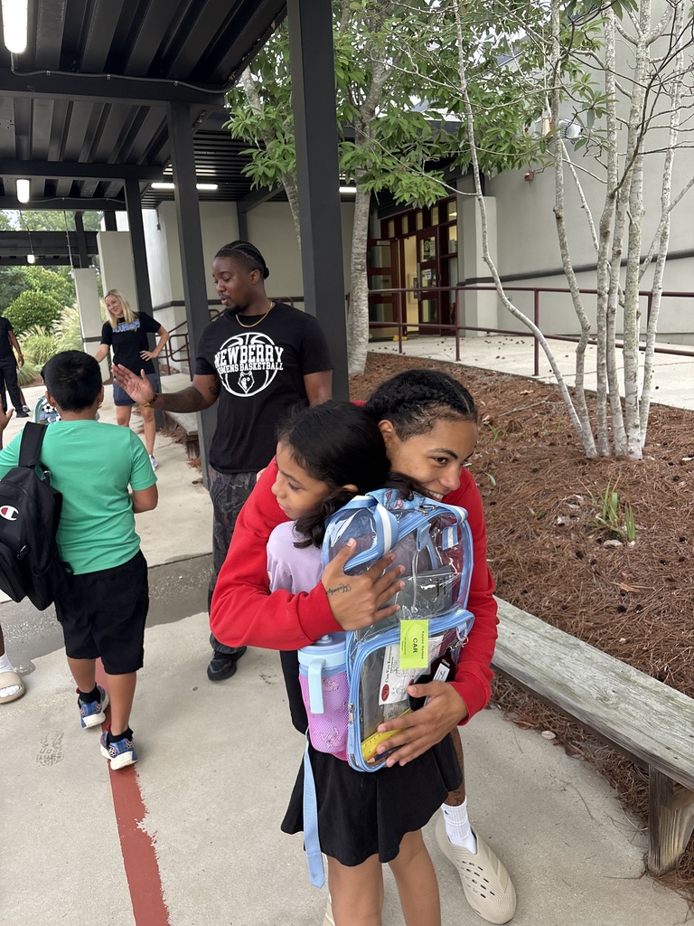 Wide shot of Newberry College basketball women players greeting a student.