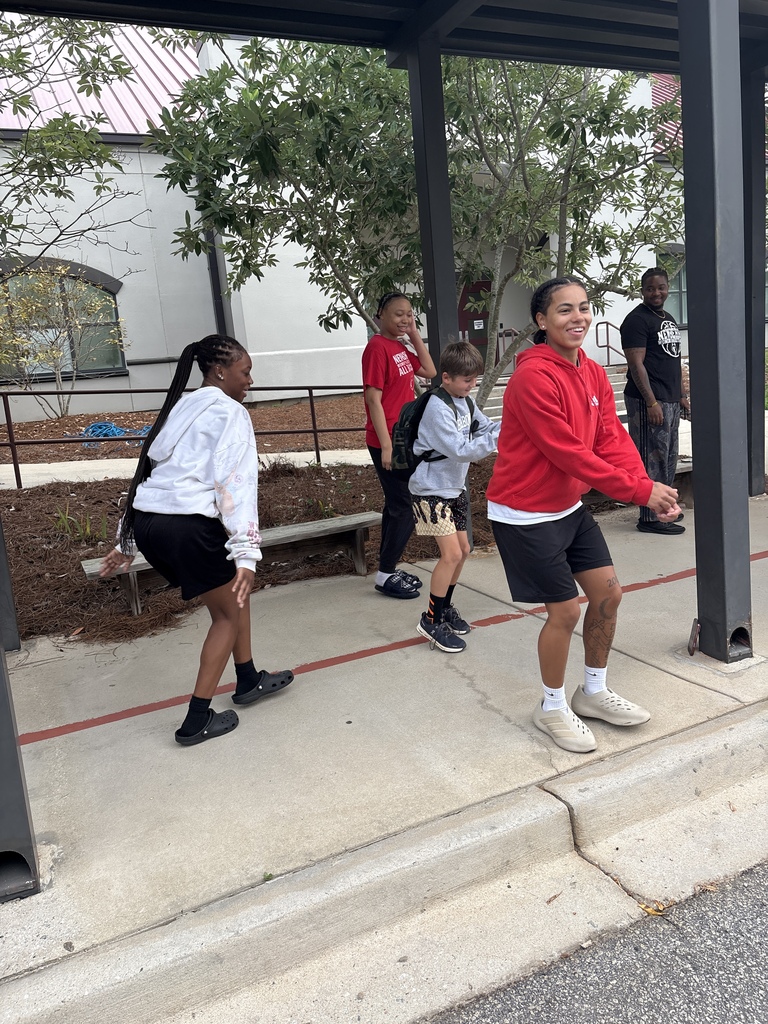 Wide shot of Newberry College basketball women players greeting a student.