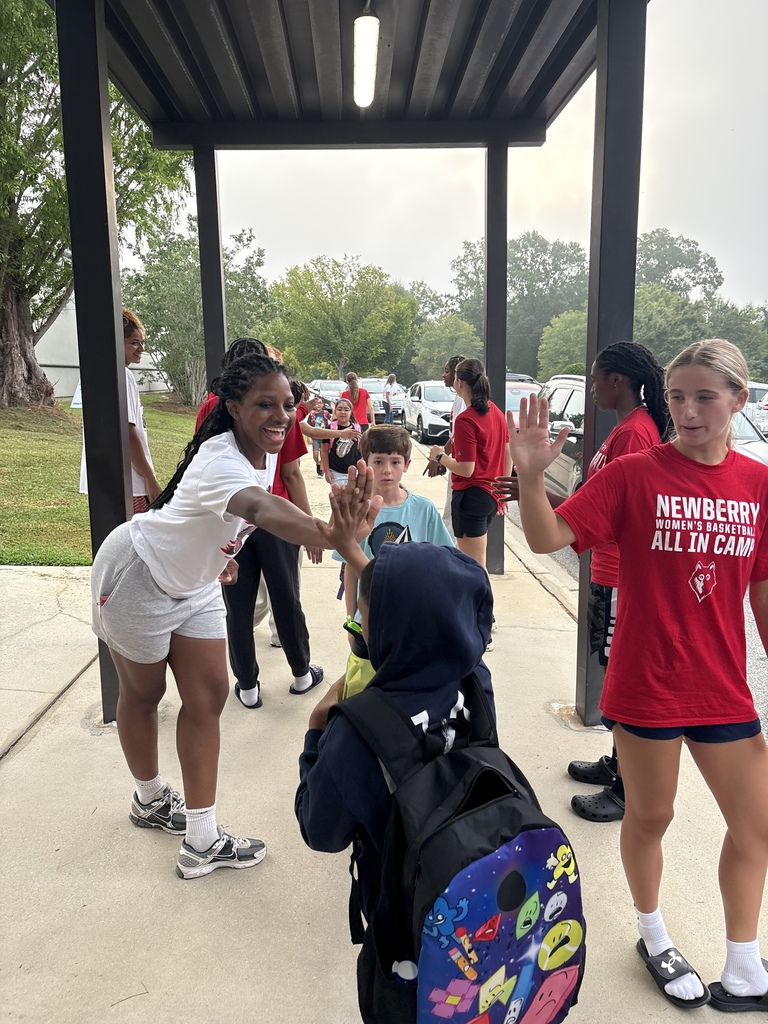 Wide shot of Newberry College basketball women players greeting a student.