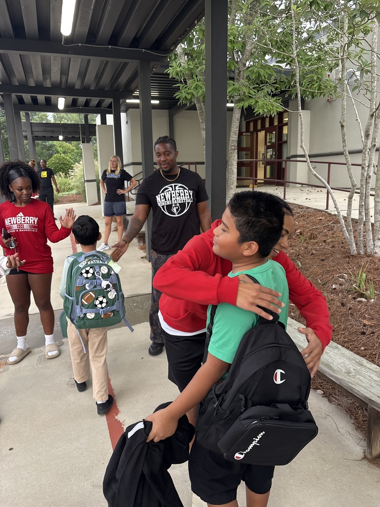 Wide shot of Newberry College basketball women players greeting a student.