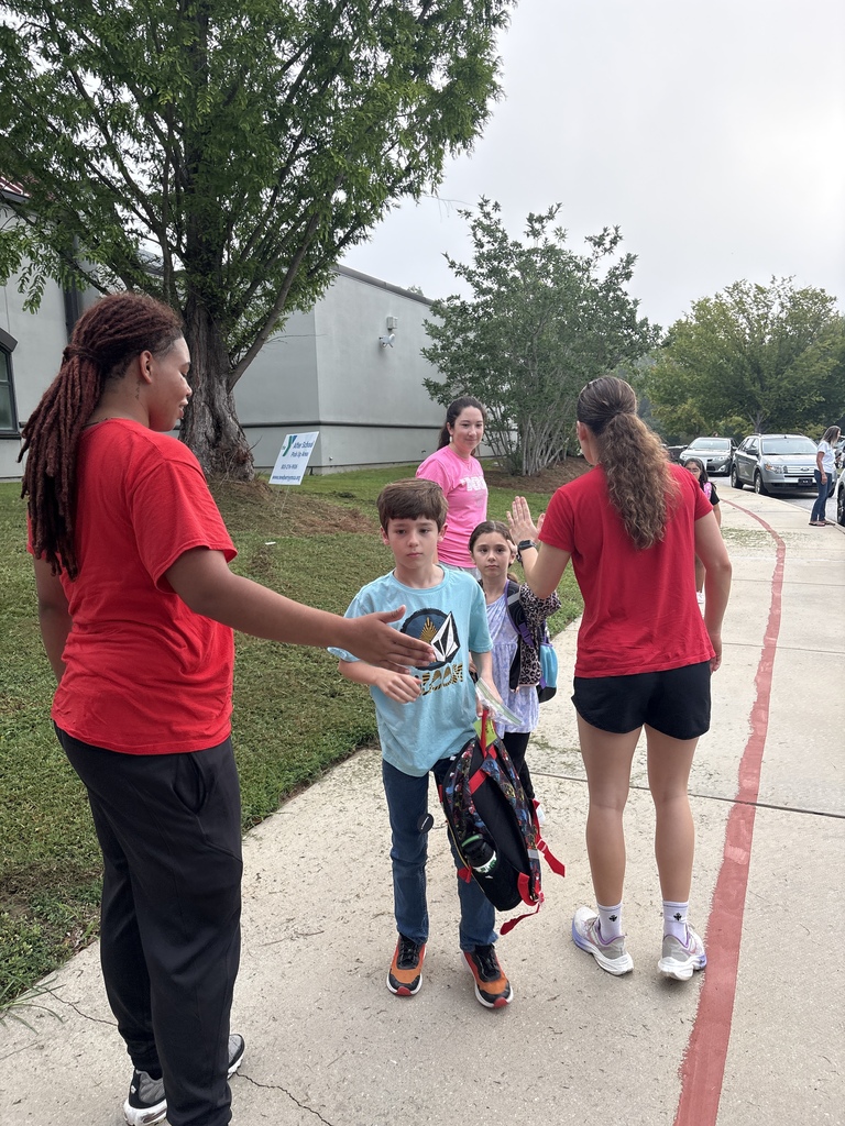 Wide shot of Newberry College basketball women players greeting a student.