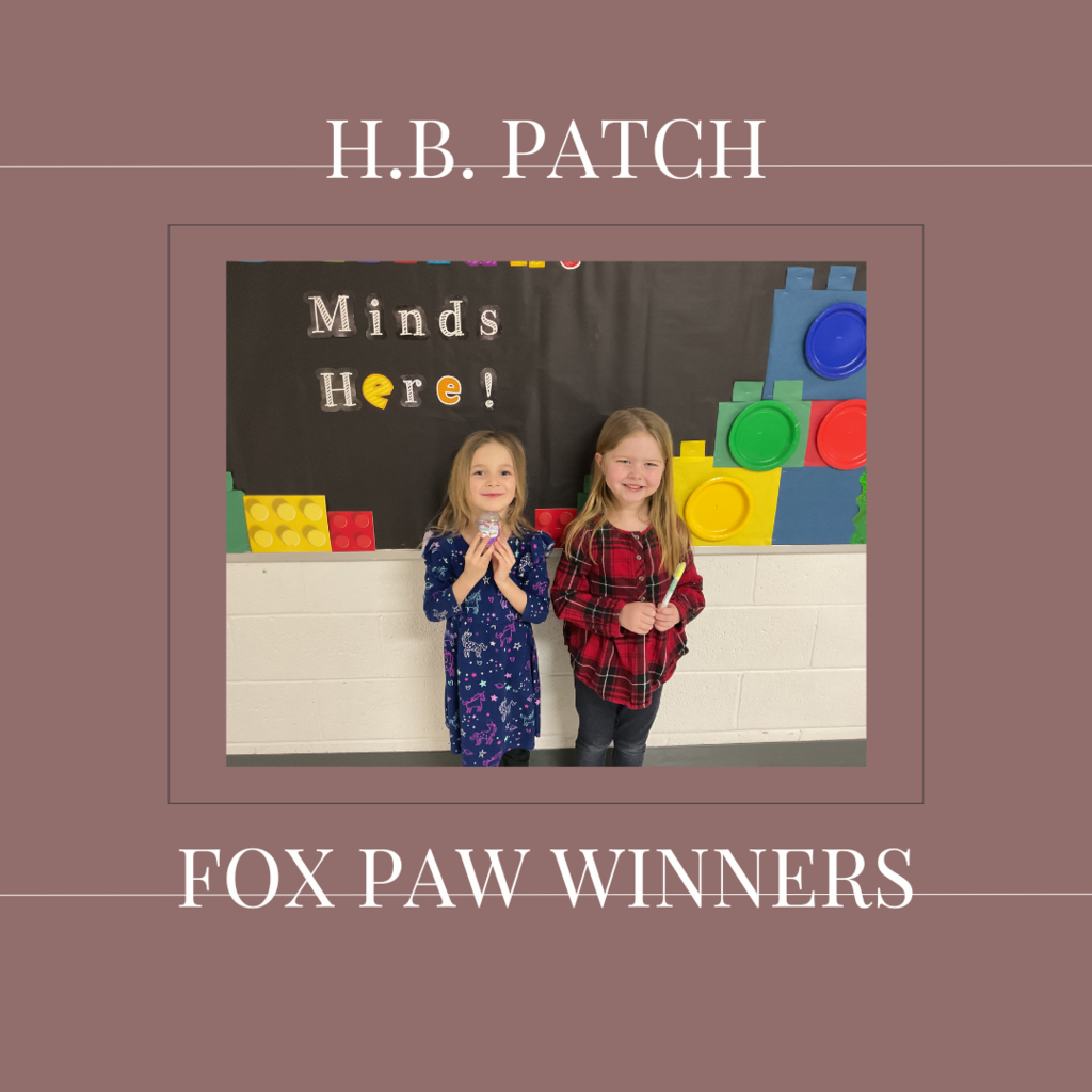 A couple of early elementary students standing in front of a bulletin board.