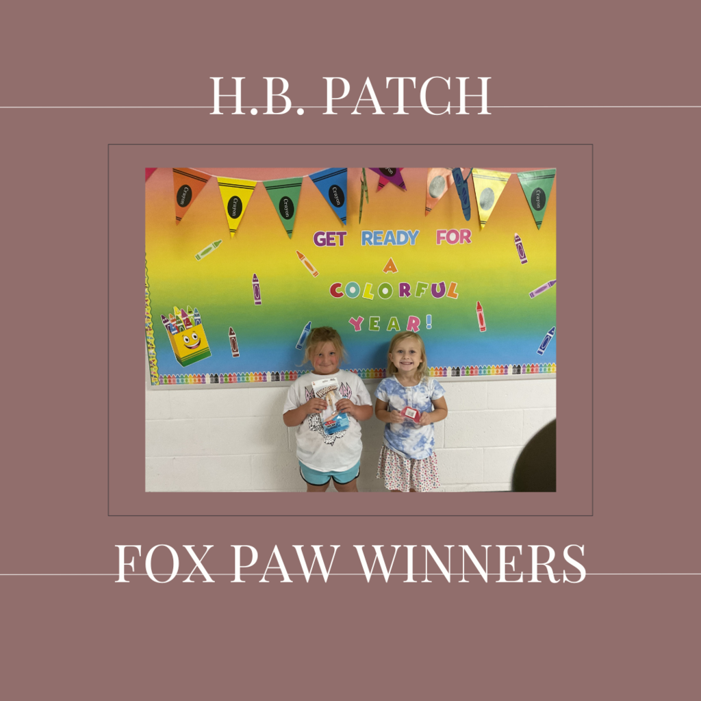 A couple of early elementary students standing in front of a bulletin board. 