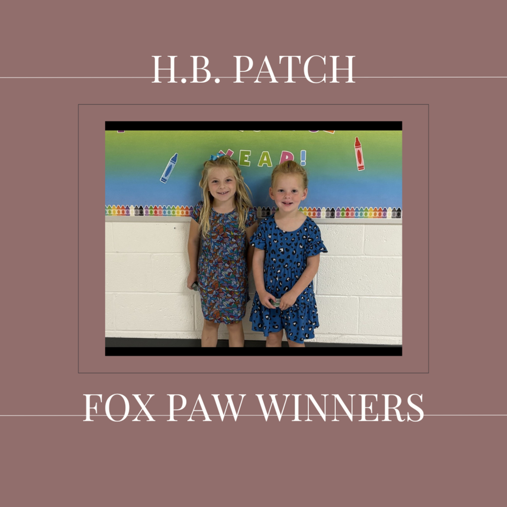 A couple of early elementary students standing in front of a bulletin board. 