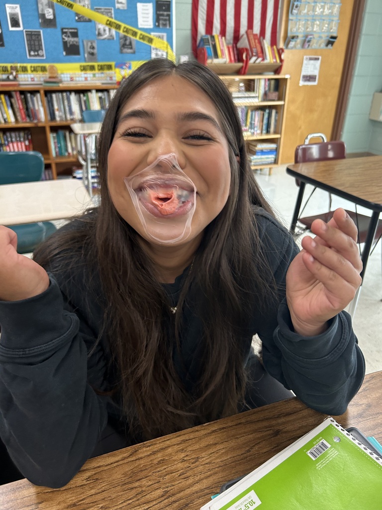 A high school student with a popped bubble from bubble gum on her face.