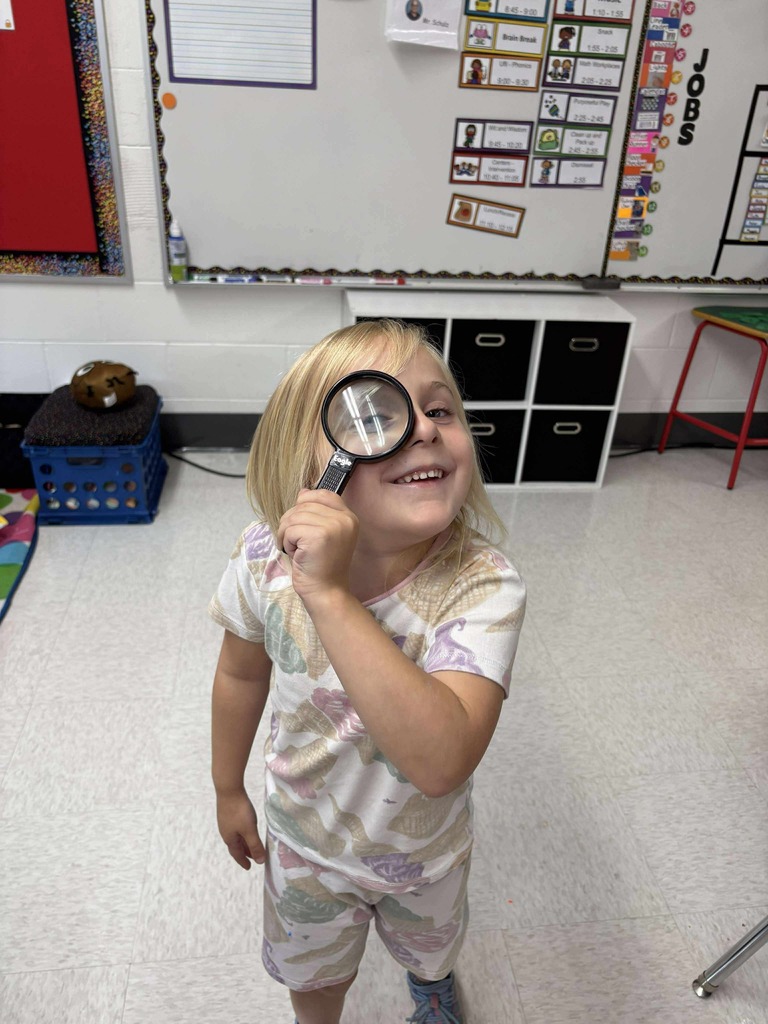 One young learner holding a magnifying glass to their eye.