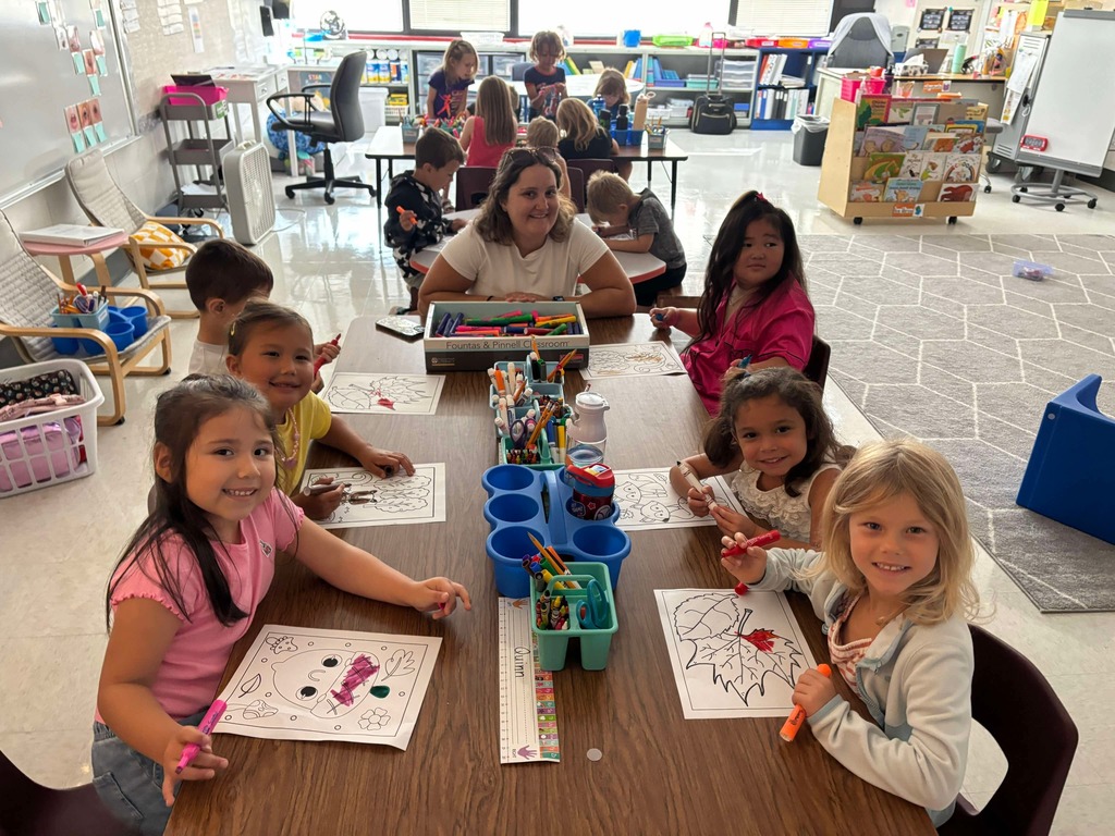 Young learners at tables working with an adult.