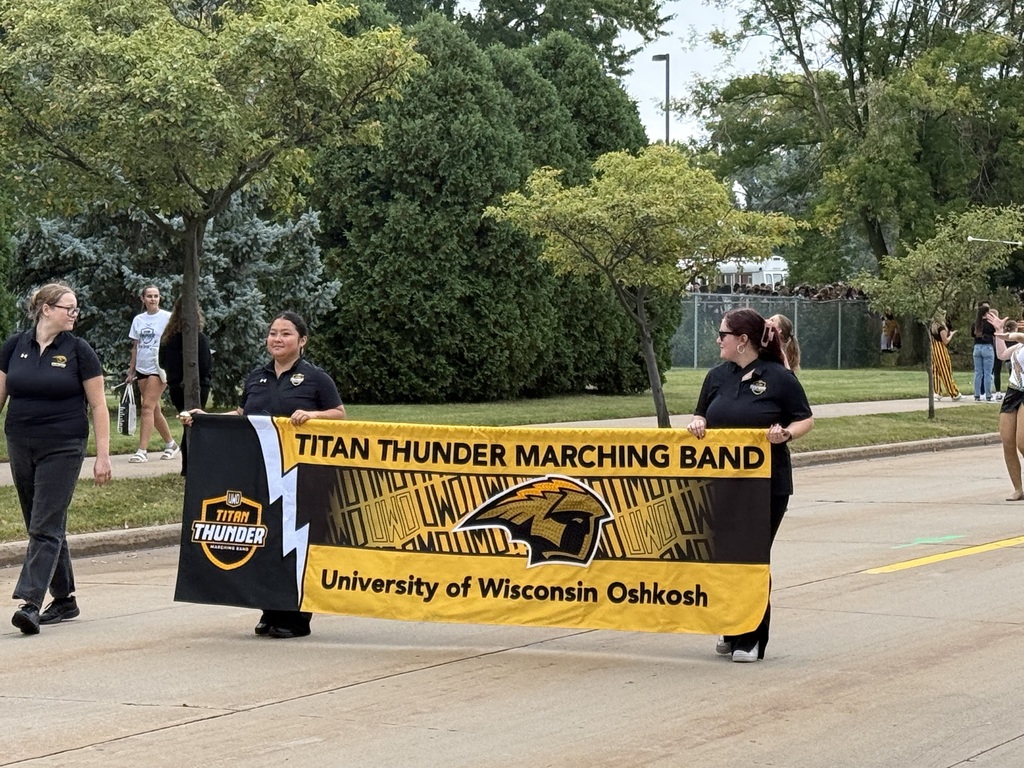 Two individuals carrying a banner that says "Titan Thunder Marching Band"