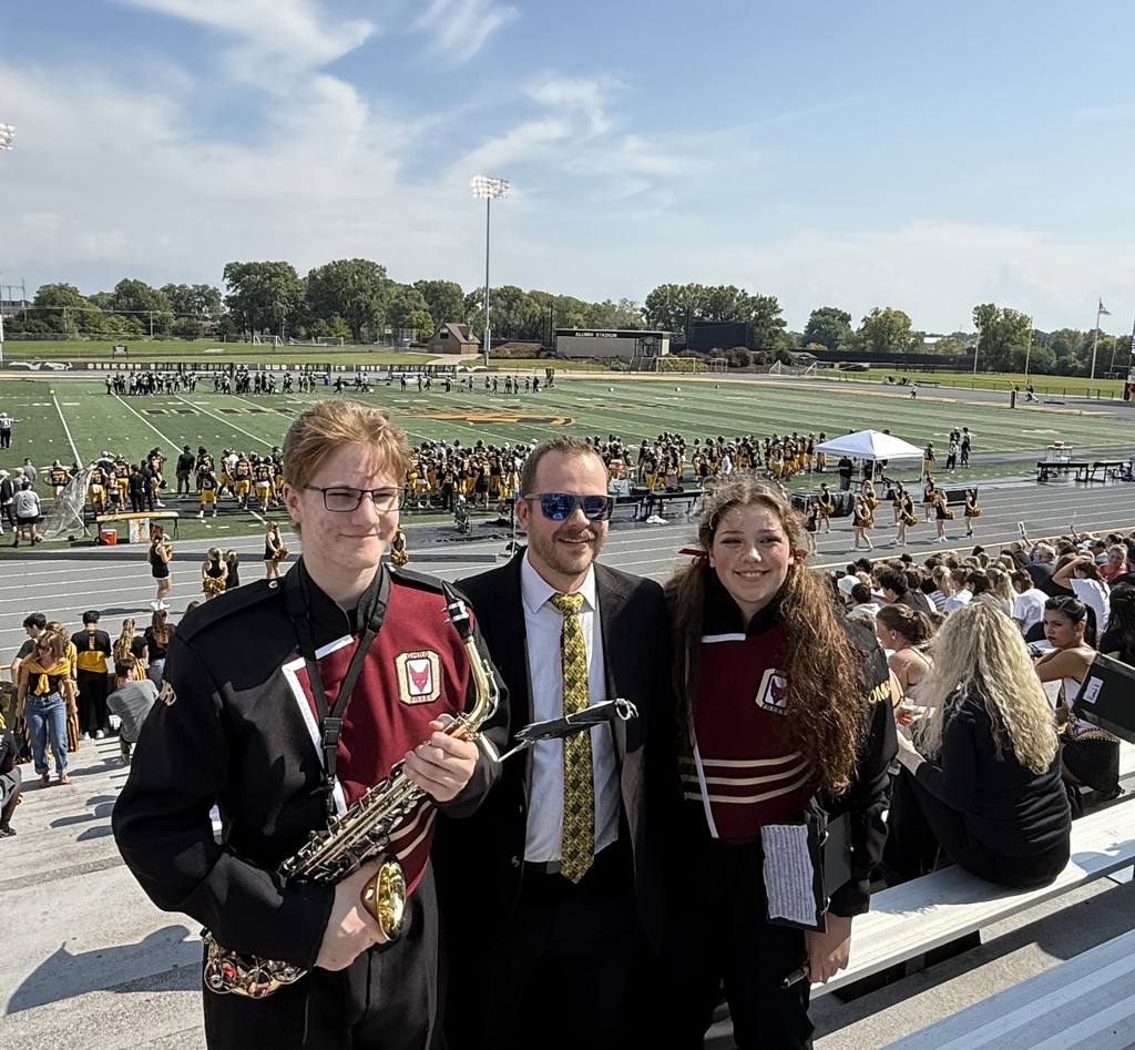 A band director standing with two of his students.