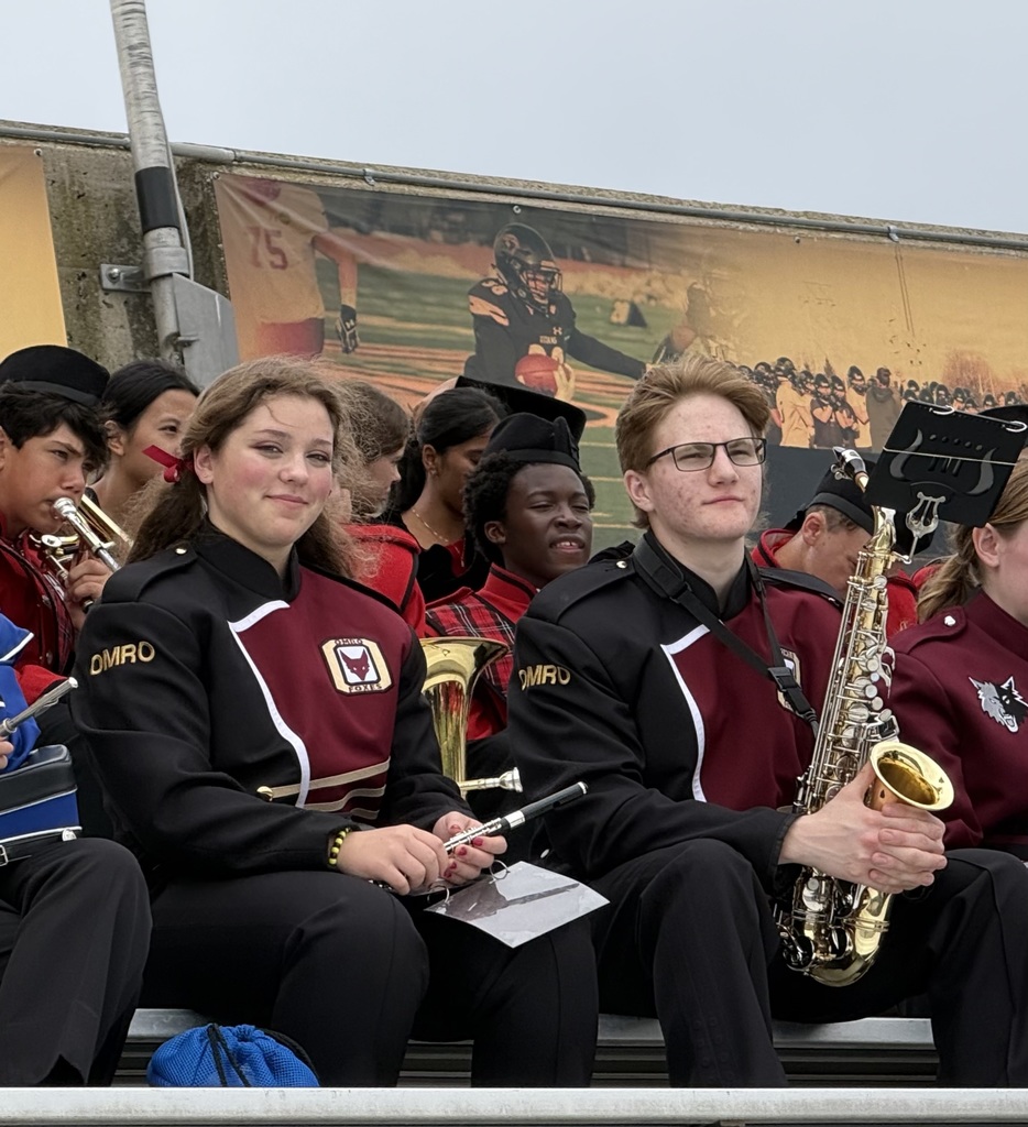 Two high school students wearing their band uniforms and holding their instruments.
