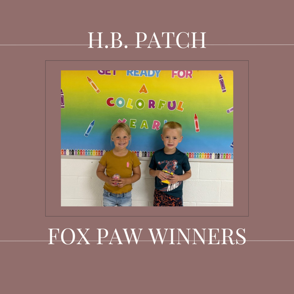 A couple of early elementary students standing in front of a bulletin board. 