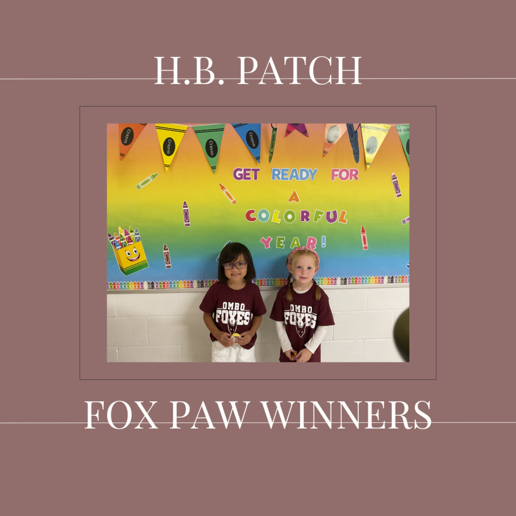 A couple of early elementary students standing in front of a bulletin board. 