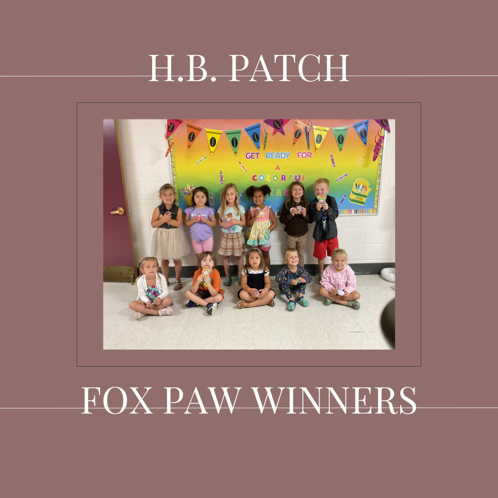 A group of early elementary students standing in front of a bulletin  board.