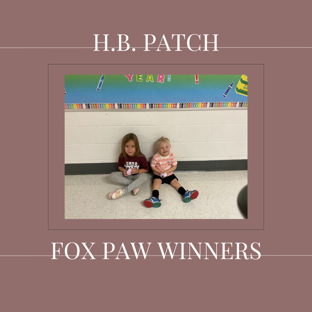 A couple of early elementary students standing in front of a bulletin board.