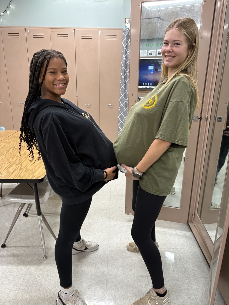 Two high school students wearing a preganancy simulator and posing for a picture.