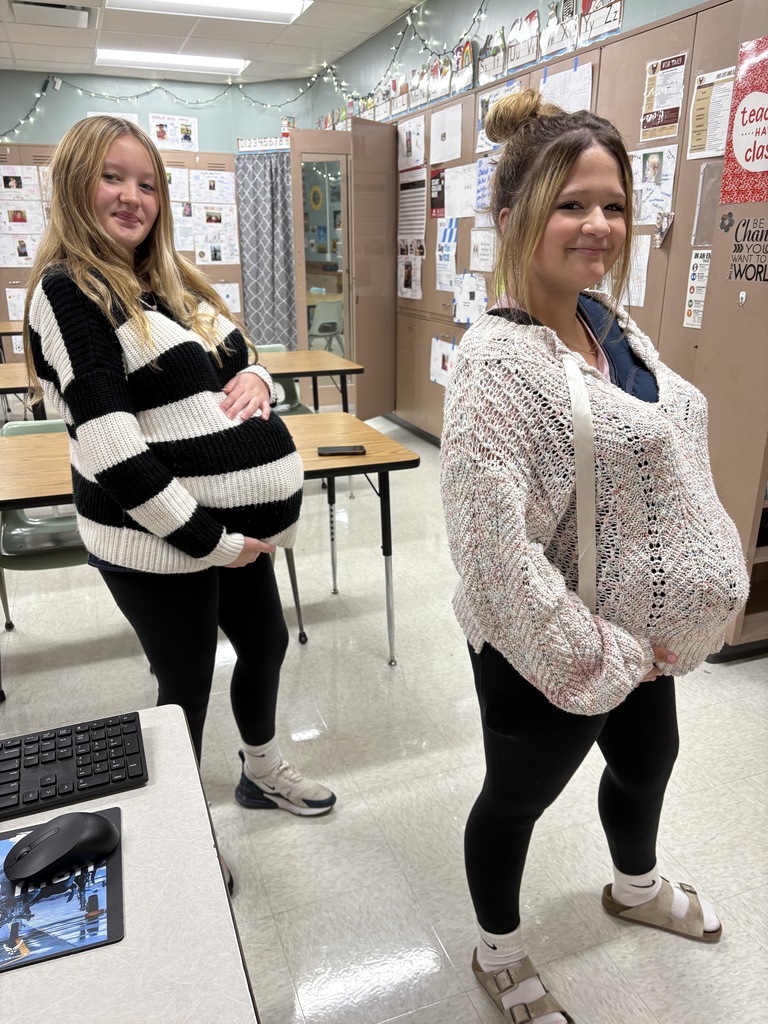 Two high school students wearing a preganancy simulator and posing for a picture.