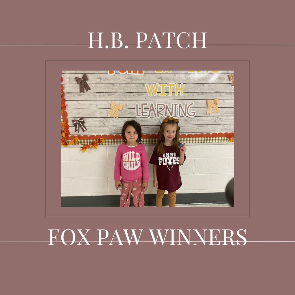 A couple of early elementary students standing in front of a bulletin board. 