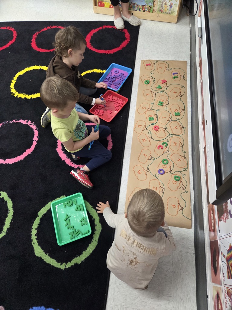 Three early learners working on letter matching.