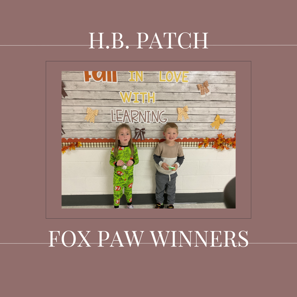 A couple of early elementary students standing in front of a bulletin board. 