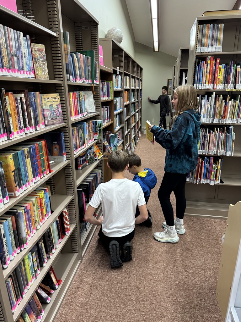 Middle school students picking out books in a public library.