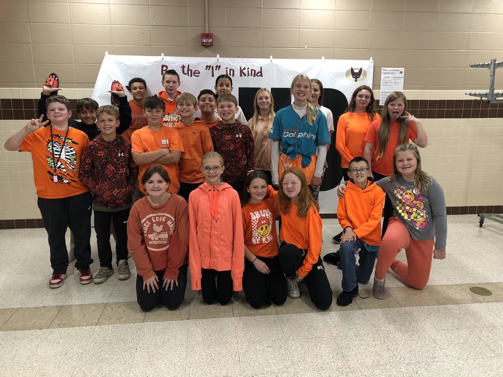 A group of middle school students, wearing orange, gathered together for a picture. 