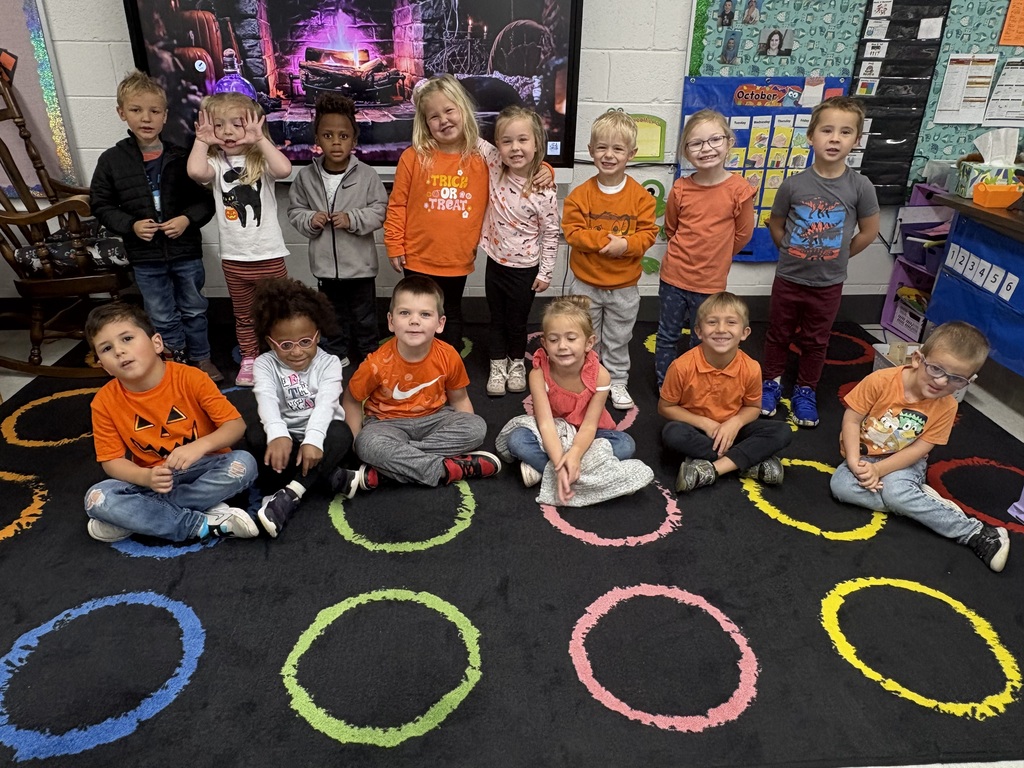 Early elementary students gathered together, wearing orange.