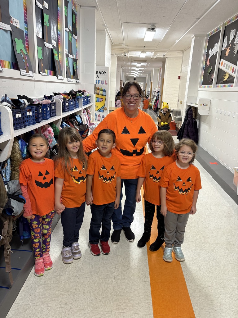 Early elementary students gathered together with their teacher, wearing orange.