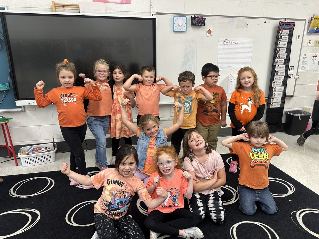 Early elementary students gathered together, wearing orange.
