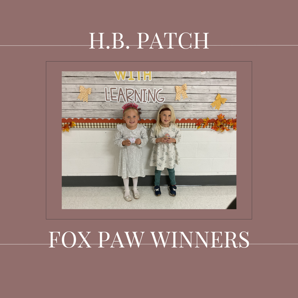 A couple of early elementary students standing in front of a bulletin board.