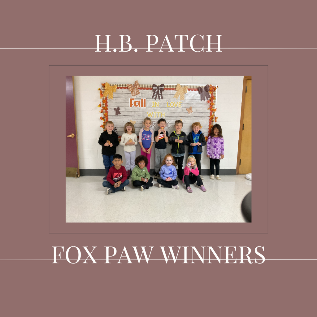 A group of early elementary students standing in front of a bulletin  board.
