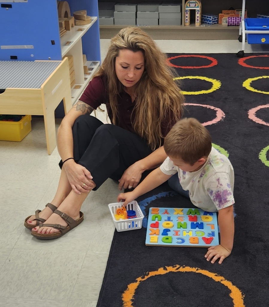 An adult and early elementary student working on the floor together.