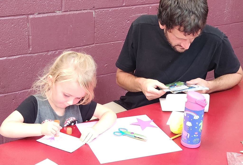 An adult and early elementary student working together at a table. 