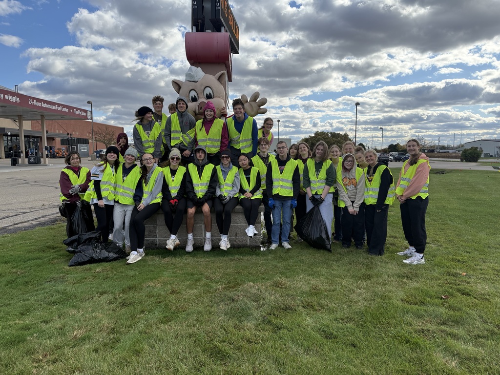 High school students in bright vests standingtogether outside after a highway cleanup.