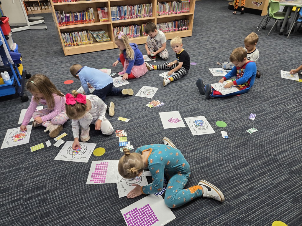 Early learners completing sticker art pumpkins in the media center.