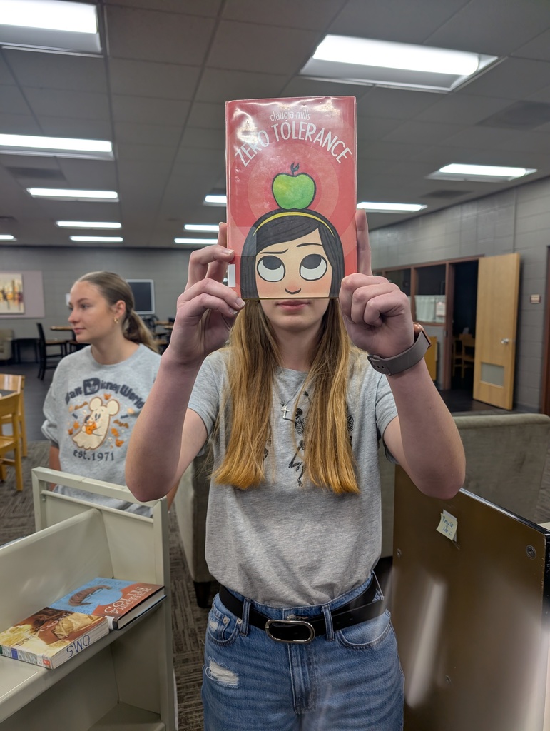 A "book face" picture of a person posing with a book to make it look like they are a part of the cover.