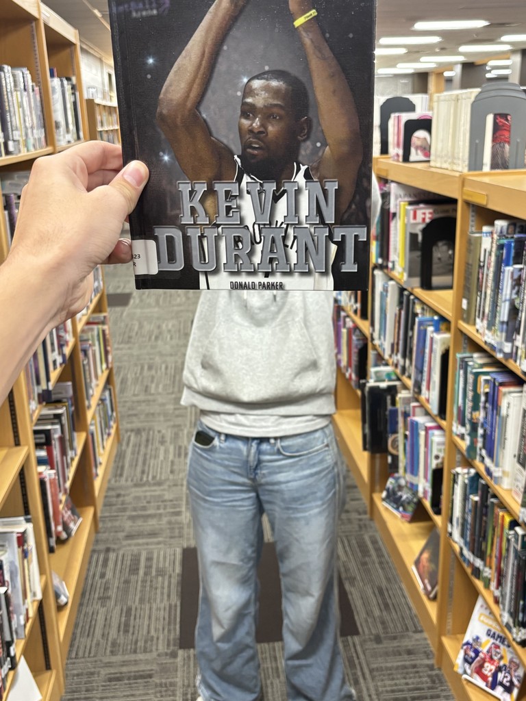 A "book face" picture of a person posing with a book to make it look like they are a part of the cover.