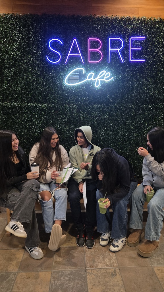5 high school students sitting together, laughing.