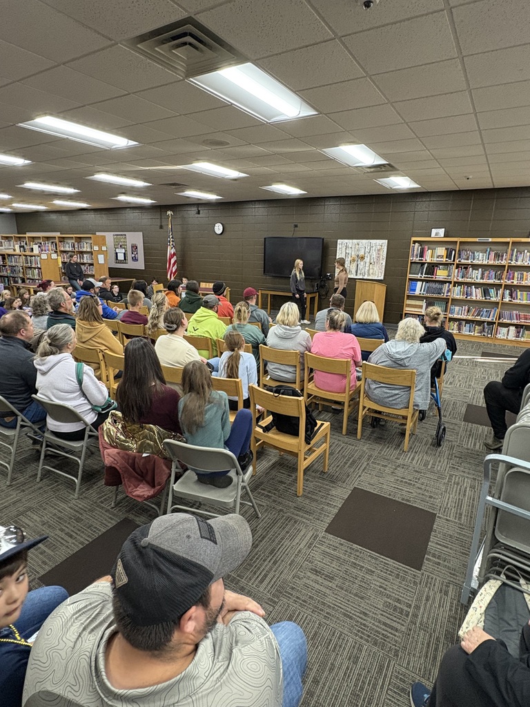Middle school students presenting in front of family members.