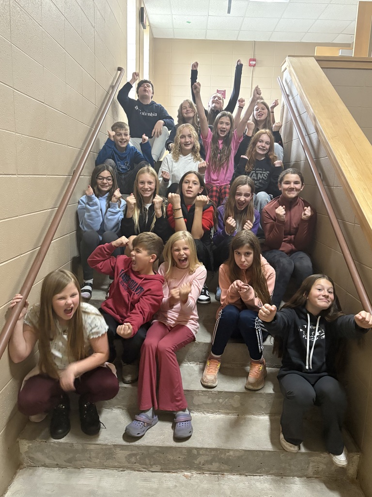 Middle school students sitting on stairs in a stairwell.