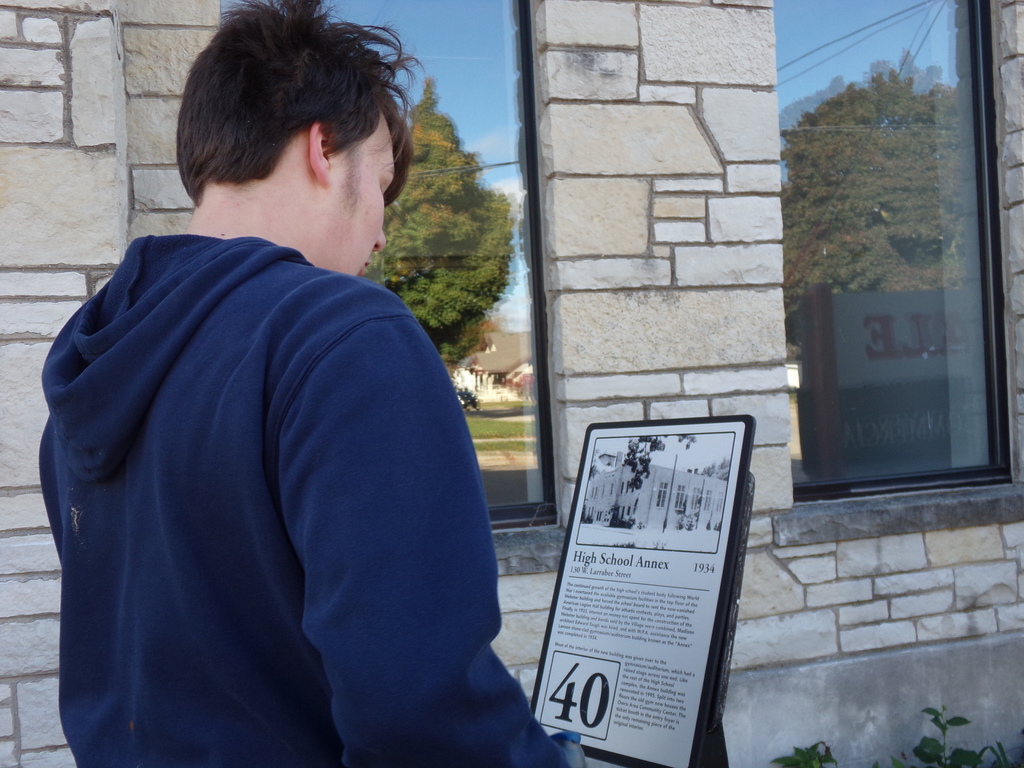 A middle school student reading a historical marker outside.