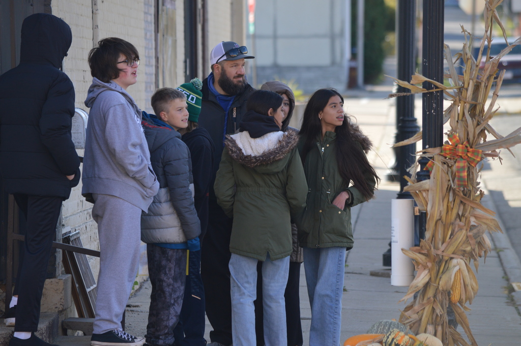 A group of middle school students looking across the road on a fall day.
