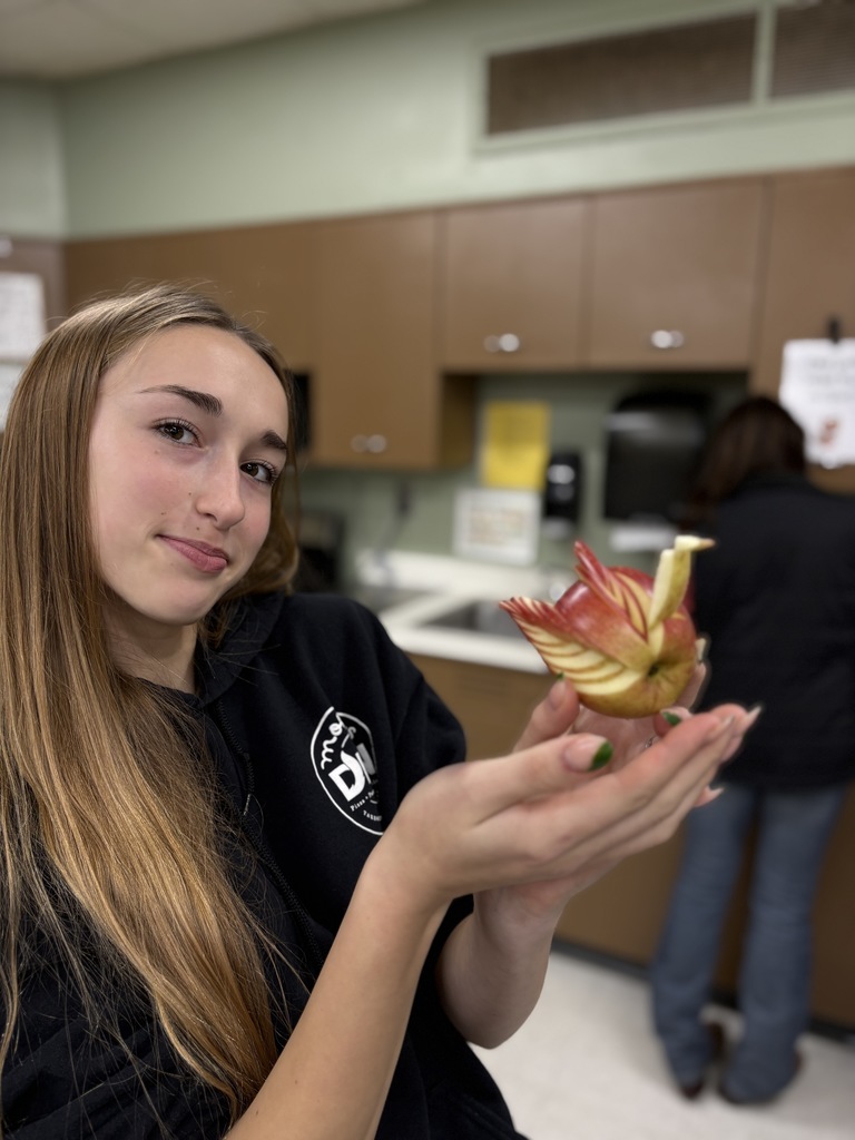 A student holding fruit that is delicately sliced.