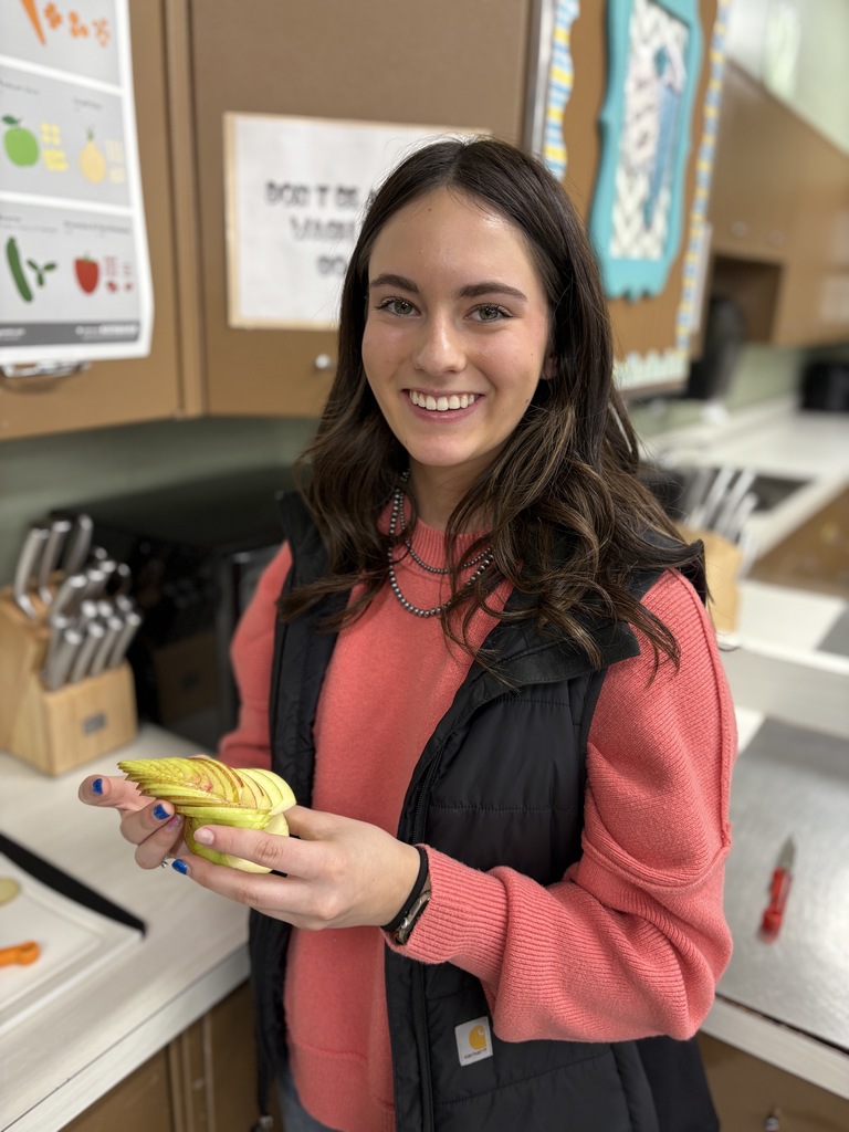 A student holding fruit that is delicately sliced.