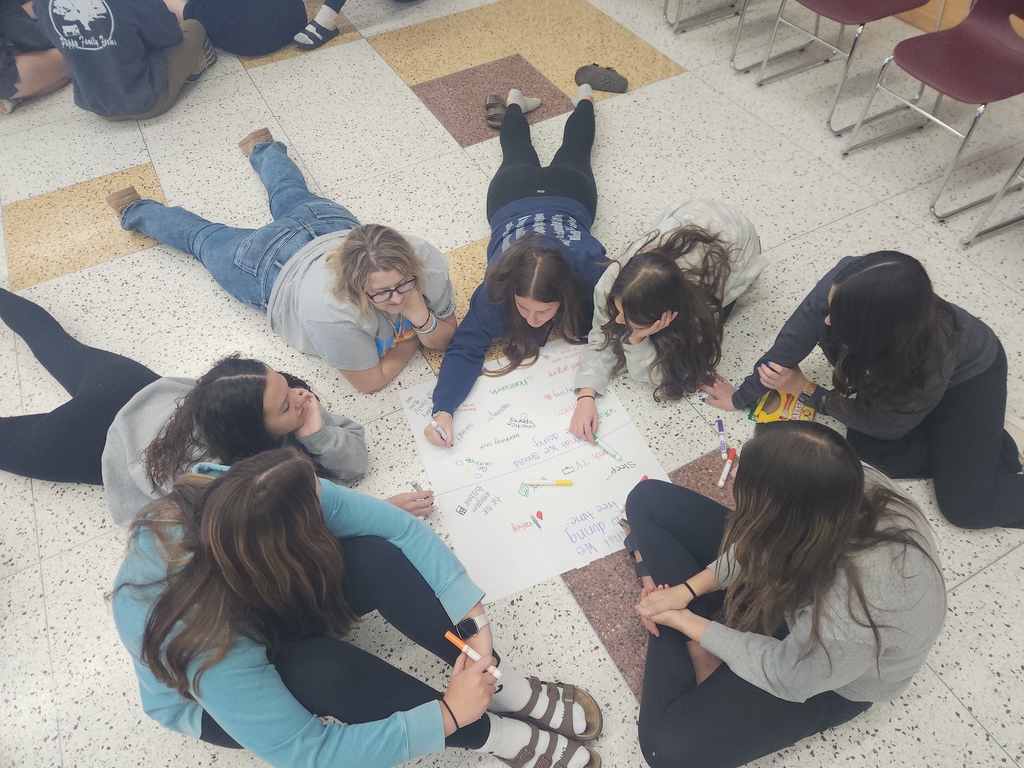High school students, in a circle, working together.