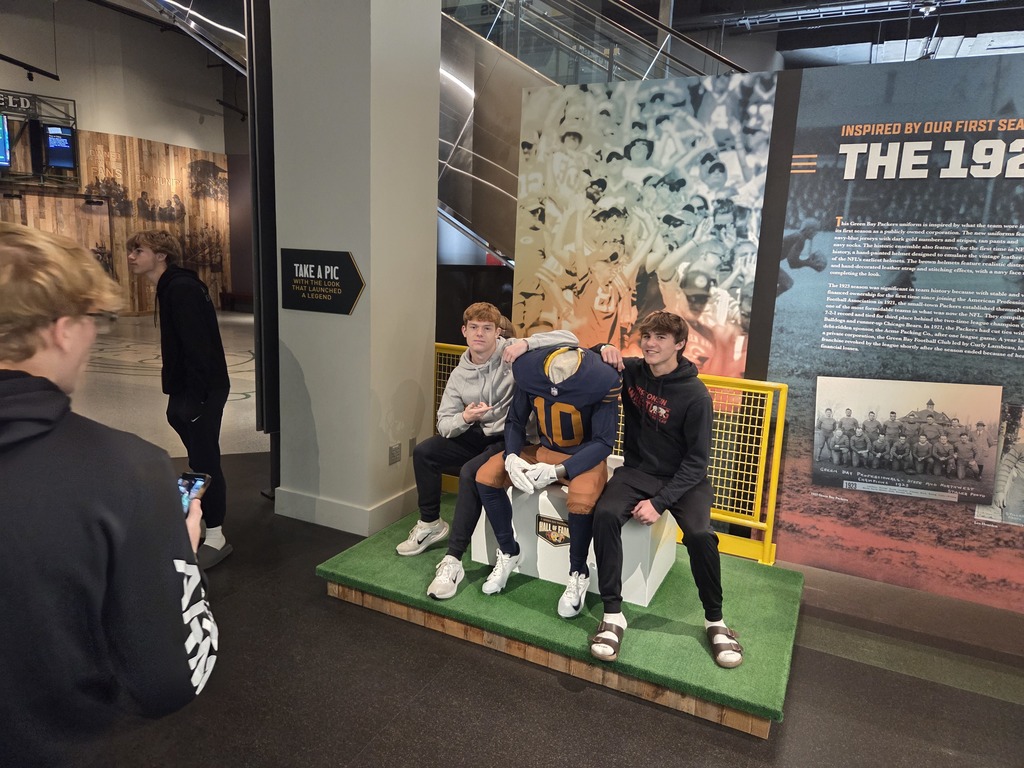 Picture of high school students sitting near a football mannequin.