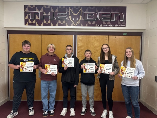 Six high school stu dents standing in front of doors to The Den.
