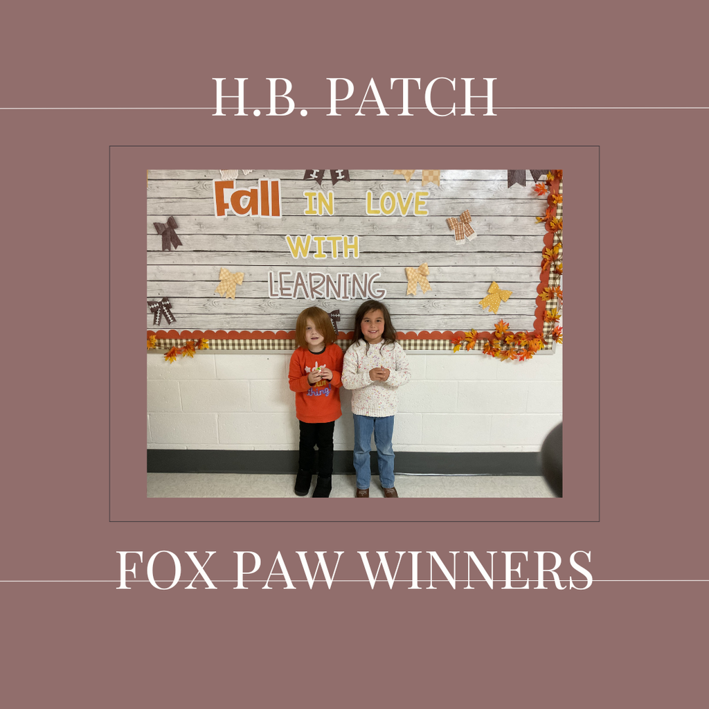 A couple of early elementary students standing in front of a bulletin board.