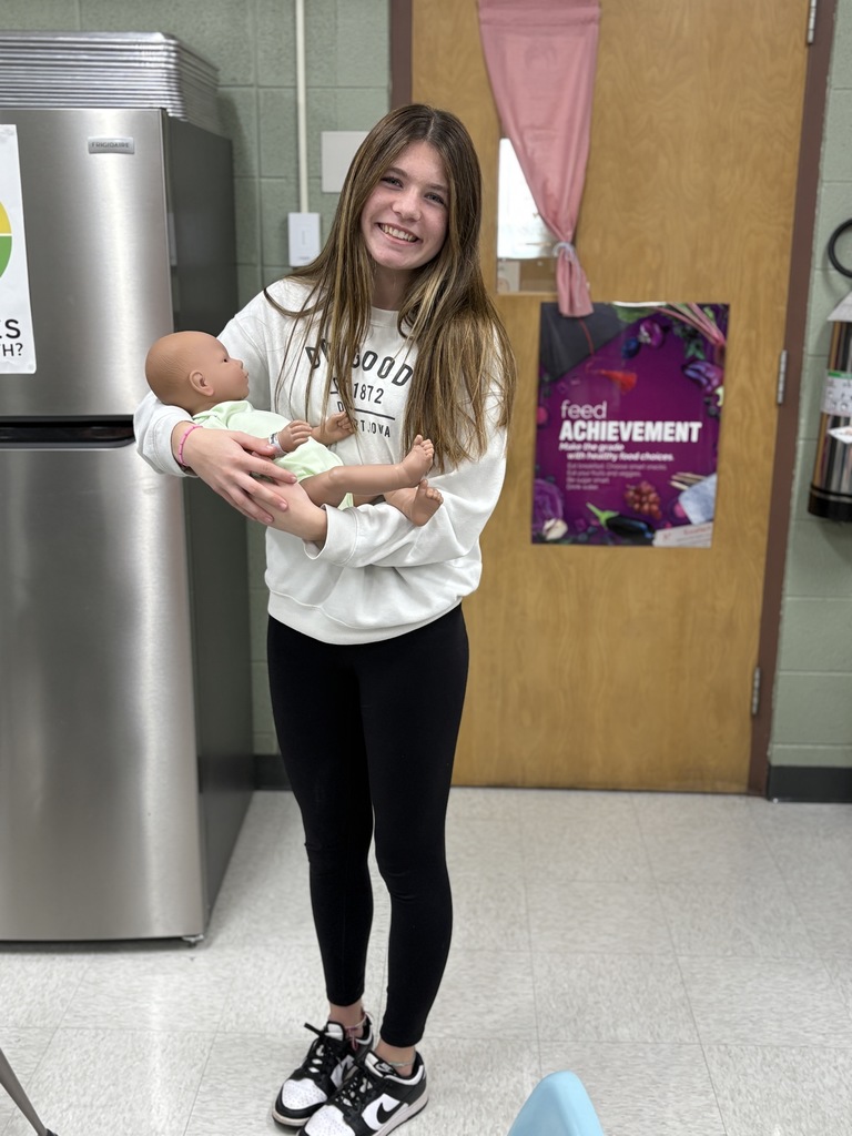 High school student practices holding a baby safely (using a doll).